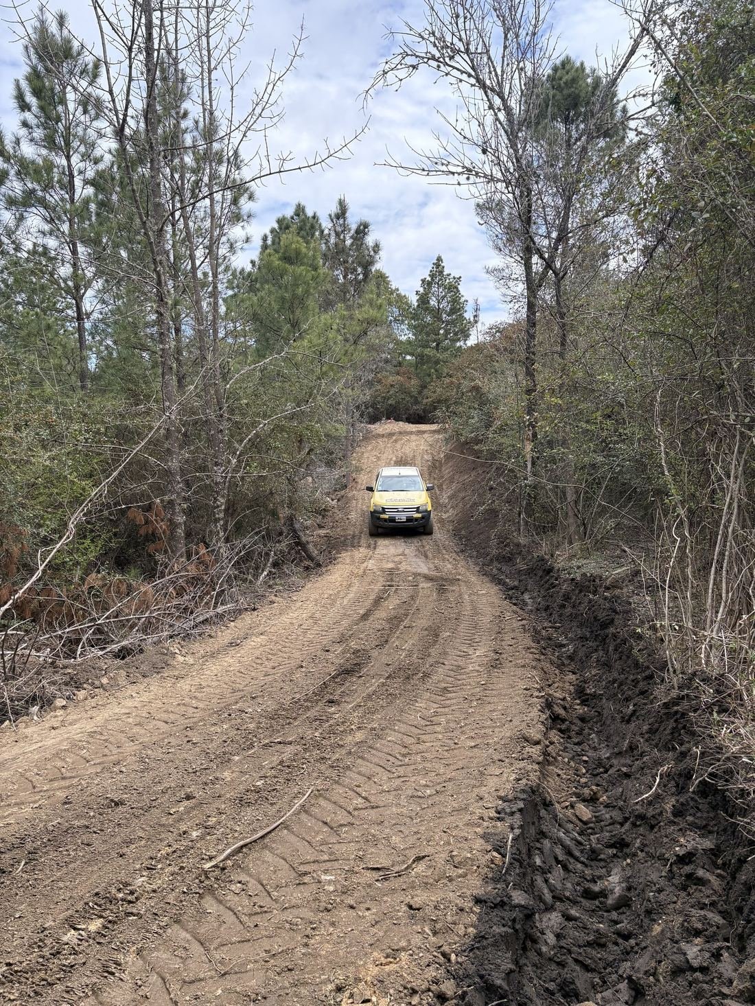 Camino de tierra recién abierto y perfilado, con la camioneta de CONSER subiendo