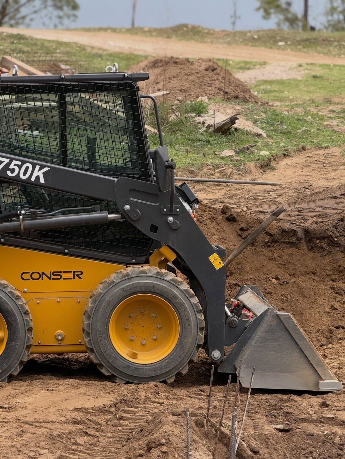 Minicargadora XC750K de CONSER nivelando dentro de un lote